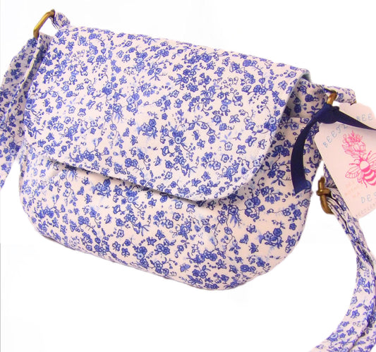 close up of blue and white floral fabric crossbody bag with whimsical butterfly motifs. Lightweight boho crossbody bag with enchanting flower fabric perfect for festivals and outings